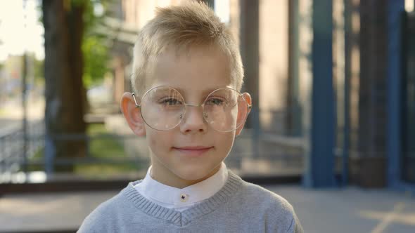 Close Up View of the Schoolboy Stabding Looking at the Camera Wearing Glasses and Smiling alt