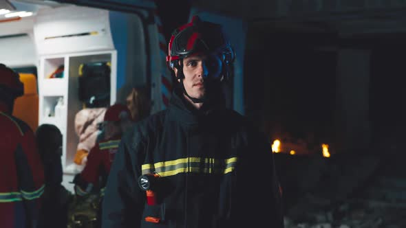 Male Rescuer Standing Near Ambulance Car at Night alt
