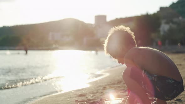 A Boy Plays with Toys on the Beach in the Sand alt