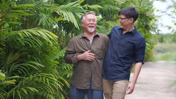 Happy Middle aged son and senior father talking having fun enjoy conversation in the park alt