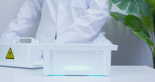 Doctor or Scientist Wearing Sterile Gloves Closes a Container for Transportation with Smoking alt