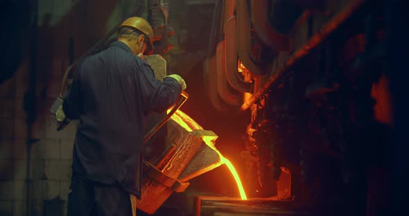 Foundry, a man pours molten metal into the mold