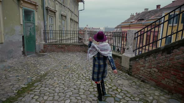 Back view of woman walking and spinning around herself approching the handrail. alt