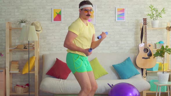 Funny Athletic Man in the Style of 80s Is Engaged with Dumbbells and Posing at the Camera alt