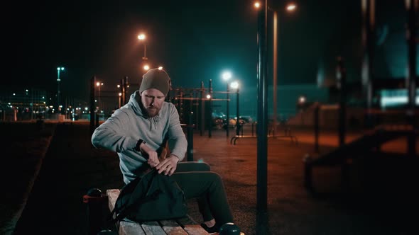 Man with Training Bag on Athletic Ground at Night. alt