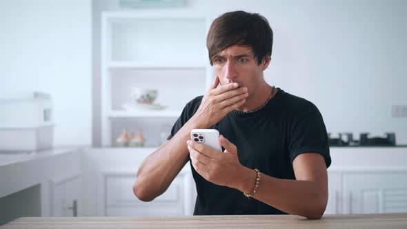 Shocked Young Man Using Smartphone Loses Dissatisfied with Bad News at Home alt