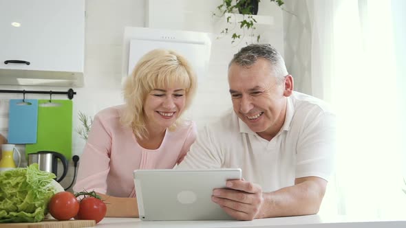 Retired Family Watching Video on Tablet Computer in Apartment Kitchen alt