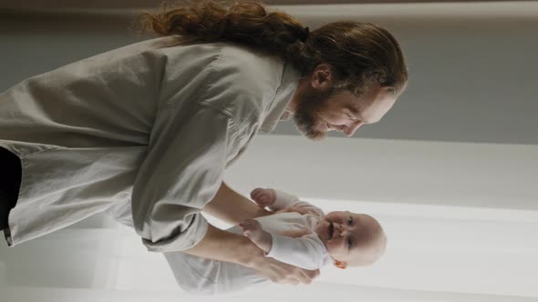 Vertical View Caucasian Adult Father Loving Caring Daddy Holding Baby Daughter Little Son Throwing alt