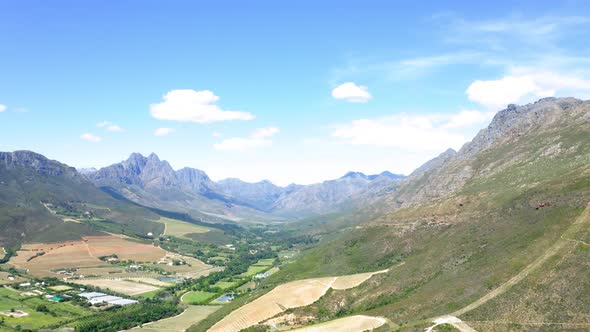 Aerial drone of green and brown farmland valley between mountains with hiking, Stellenbosch, Hottent alt