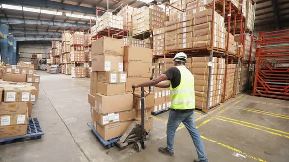 Warehouse Worker Pushes A Hand Pallet Truck With Boxes alt