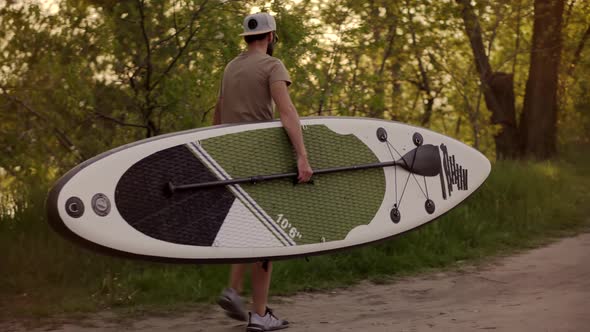Tourist Carries Sup Board On Vacation. Tourist Floating Standup Paddle Board. alt