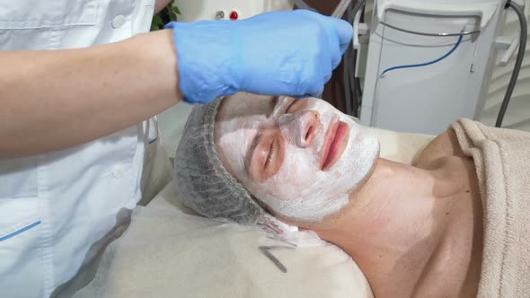 Happy Man Getting Facial Masks at Beauty Salon, Smiling with His Eyes Closed alt