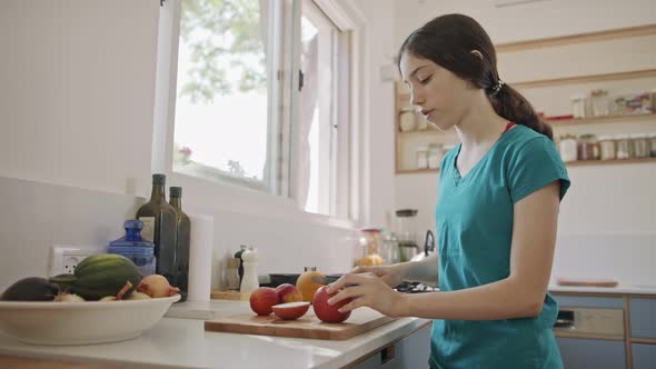 Teenage girl working cutting fruit for breakfast in the kitchen alt
