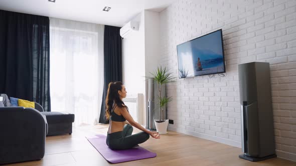 Woman Watching Yoga Tutorial and Sitting in Lotus Pose alt