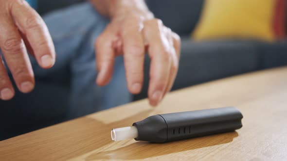 Man with Parkinson's disease using medical Cannabis in vaporizer to stop shaking alt