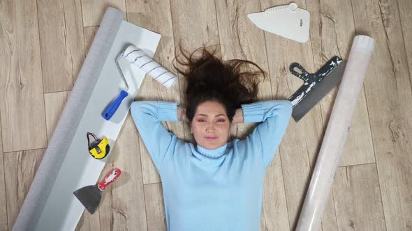 Woman Lies on Floor Among Scattered Building Materials alt