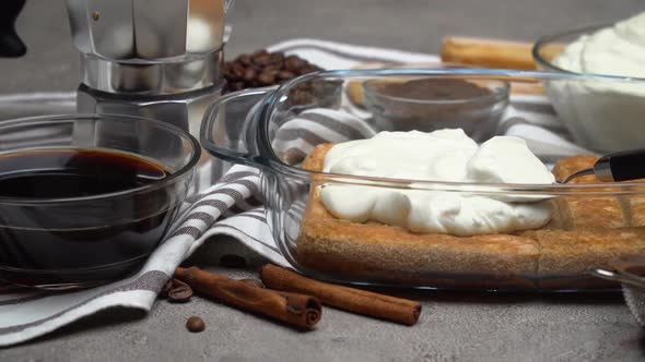Italian Savoiardi Ladyfingers Biscuits and Cream in Baking Dish, Coffe Maker on Concrete Background alt