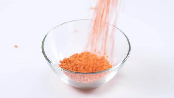 Red lentils in a glass bowl on white background. Healthy organic food diet concept.