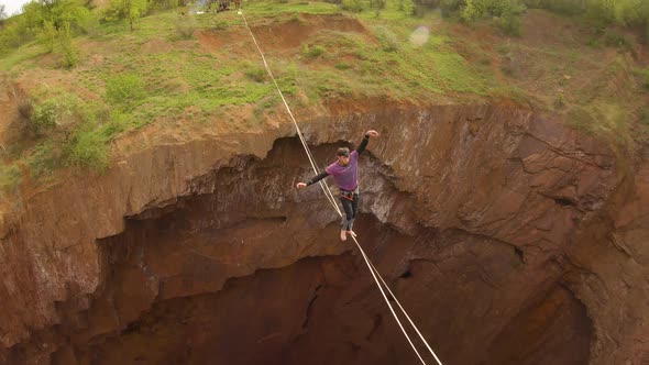 Stunning View on the Slackliner Walking on the Tightrope Over the Huge Pit alt