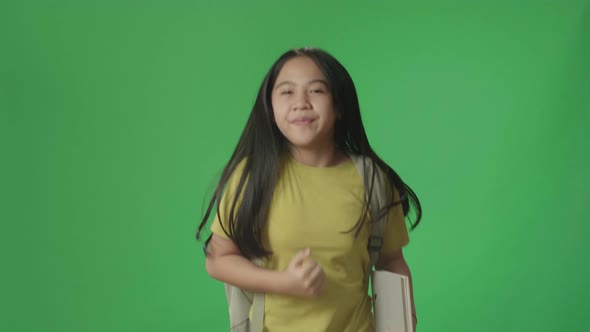Asian Girl Student Holding Book While Running To School On Green Screen Chroma Key alt