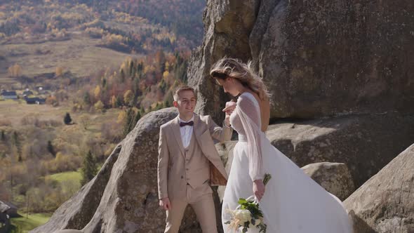 Majestic View of Rock Mountain and Beautyiful Newlyweds Who Approach to Each Other alt