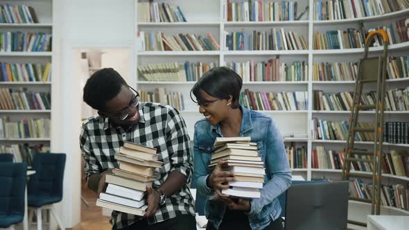 Young African Couple Holding a Bunch of Books in the Hands  alt