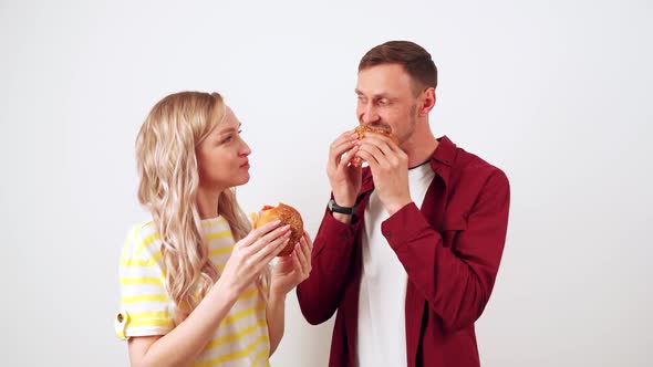 Guy with a Girl on a White Background Bite a Hamburger alt