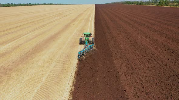 A Tractor Plows a Harvested Corn Field for Future Planting. View From Above alt