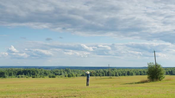 Farmer Standing in Mown Field Raising His Hands alt