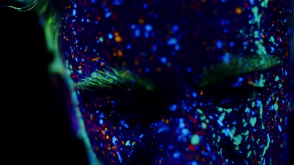 Closeup of Man's Face in Nightclub Painted with Bright Glowing Ultraviolet Paints Front View alt