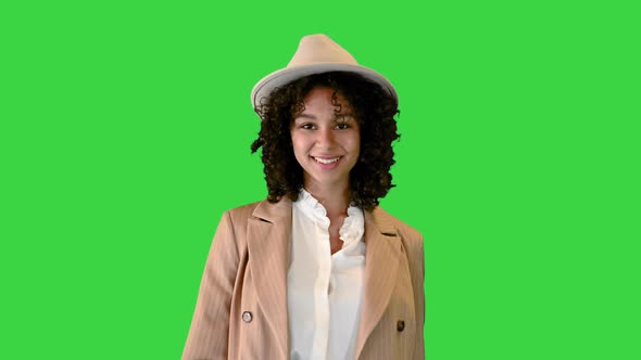 Young African American Woman in a Hat Stumbled While Walking and Smiling on a Green Screen, Chroma alt