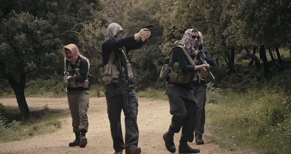 Squad of armed terrorists patrolling a forest area during combat alt