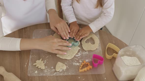 Closeup Shot Of Mother And Daughter Hands Cutting Out Different Cookie Shapes Of Dough alt