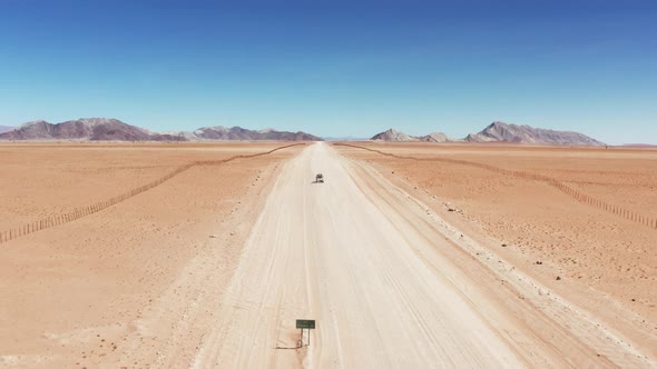 Drone Shot Of A Vehicle Driving On Dusty Trail In The Desert In Namibia. wide aerial alt