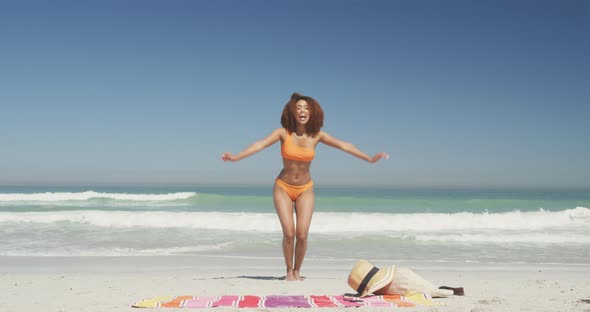 African american woman jumping at beach alt