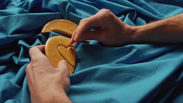 Men's Hands Break Sugar Cookies Candy in the Shape of a Heart