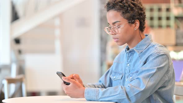 Serious African Woman Using Smartphone at Cafe  alt