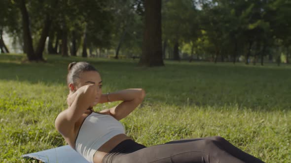 Active Sporty Fit Woman Doing Abs Crunches in Park alt