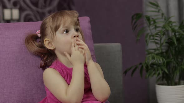 Little Child Sitting While Watching TV. Scared Kid Girl Watch Horror Movie alt