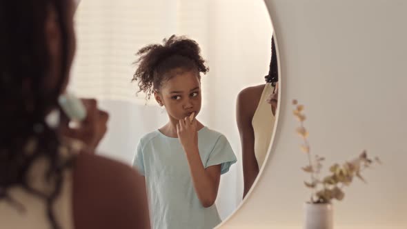 African American Mother and Daughter Brushing Teeth Together alt