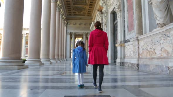 Woman with her daughter walking along the columns in Basilica of Saint Paul