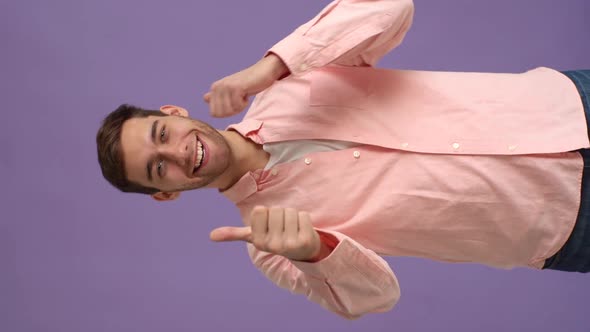 Vertical Studio Portrait of Joyful Young Man Showing Double Thumbs Up and Smiling Looking at Camera alt