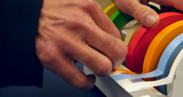 Close up on a scientist grabbing a piece of red tape to mark a piece of equipment during an experime alt