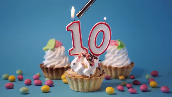 Cake Birthday Cupcake with a Burning Candle Number Ten 10 on a Blue Background alt