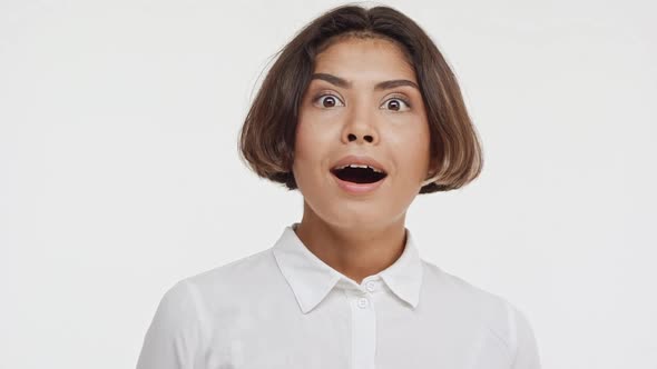Young Beautiful East Asian Female in Shirt Suprisingly Smiling Twice on White Background in alt