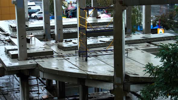 Construction site in the rain on the background of walking people, cars. The builders left