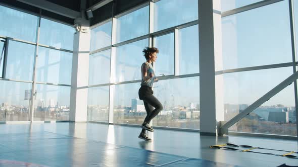 Slow Motion of Slender Sportswoman Exercising with Jumping Rope in Modern Gym alt