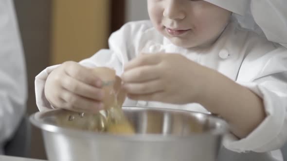 Closeup of Hands of a Young Chef Learning to Break Eggs