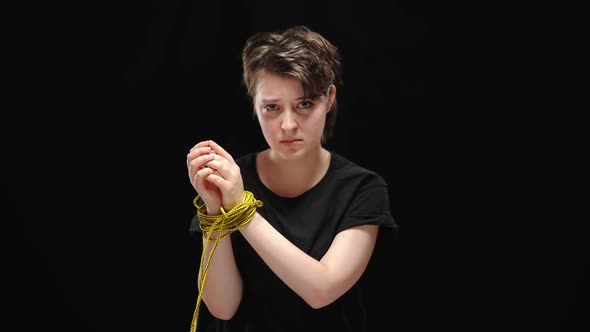 Portrait of Discriminated Young Woman Hands Tied with Rope Looking at Camera with Sad Facial alt