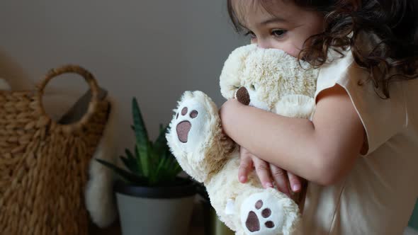 A little girl plays with her favorite teddy bear.